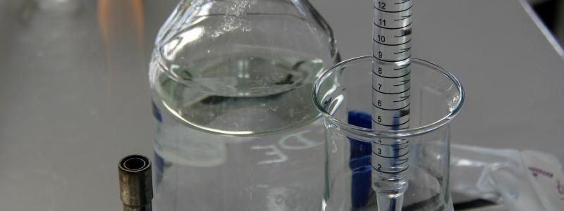 En tekniker häller vätska i en Erlenmeyerkolv med en graderad pipett i ett laboratorieutrymme. Foto: Nathan Rimoux/Unsplash