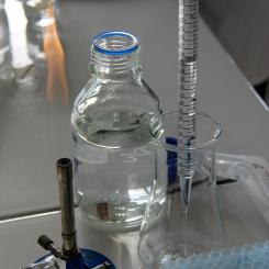 En tekniker häller vätska i en Erlenmeyerkolv med en graderad pipett i ett laboratorieutrymme. Foto: Nathan Rimoux/Unsplash